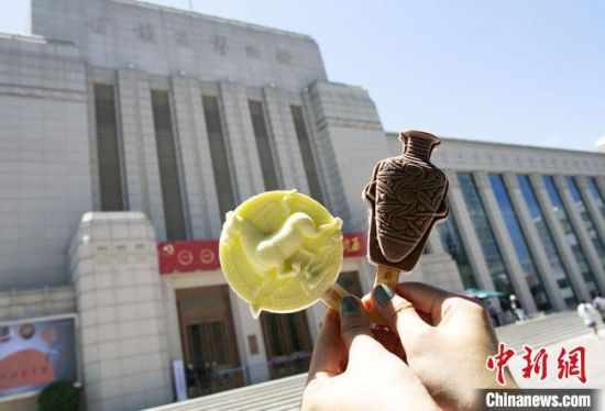 2021年7月30日，游客手拿“銅奔馬”“彩陶瓶”造型的雪糕，在甘肅省博物館前拍照打卡。　高展 攝