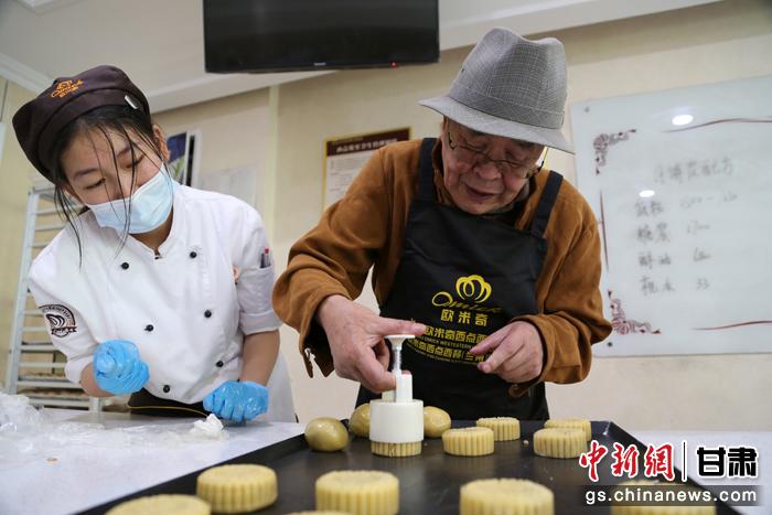 當日，受邀參加活動的臺胞臺屬代表、兩岸婚姻及子女、在甘臺商代表等歡聚一堂。圖為77歲的在甘臺胞潘天鑒制作月餅。九美旦增 攝