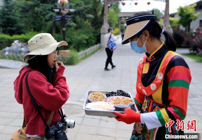 圖為身穿土族服飾的女性介紹當地特色小吃。　薛蒂 攝