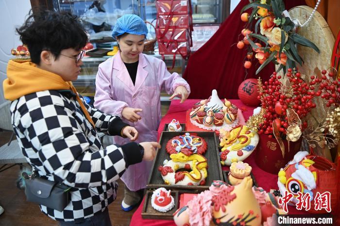 1月25日，隨著春節(jié)臨近，蘭州一花饃店“龍”元素花饃熱銷。圖為工作人員向顧客推薦“龍”元素花饃。九美旦增 攝</p><p>